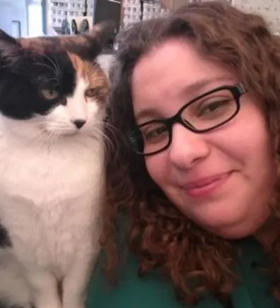 Priscilla Figueroa's staff photo from Shinnecock Animal Hospital where she is posing next to a calico cat that's on her desk.